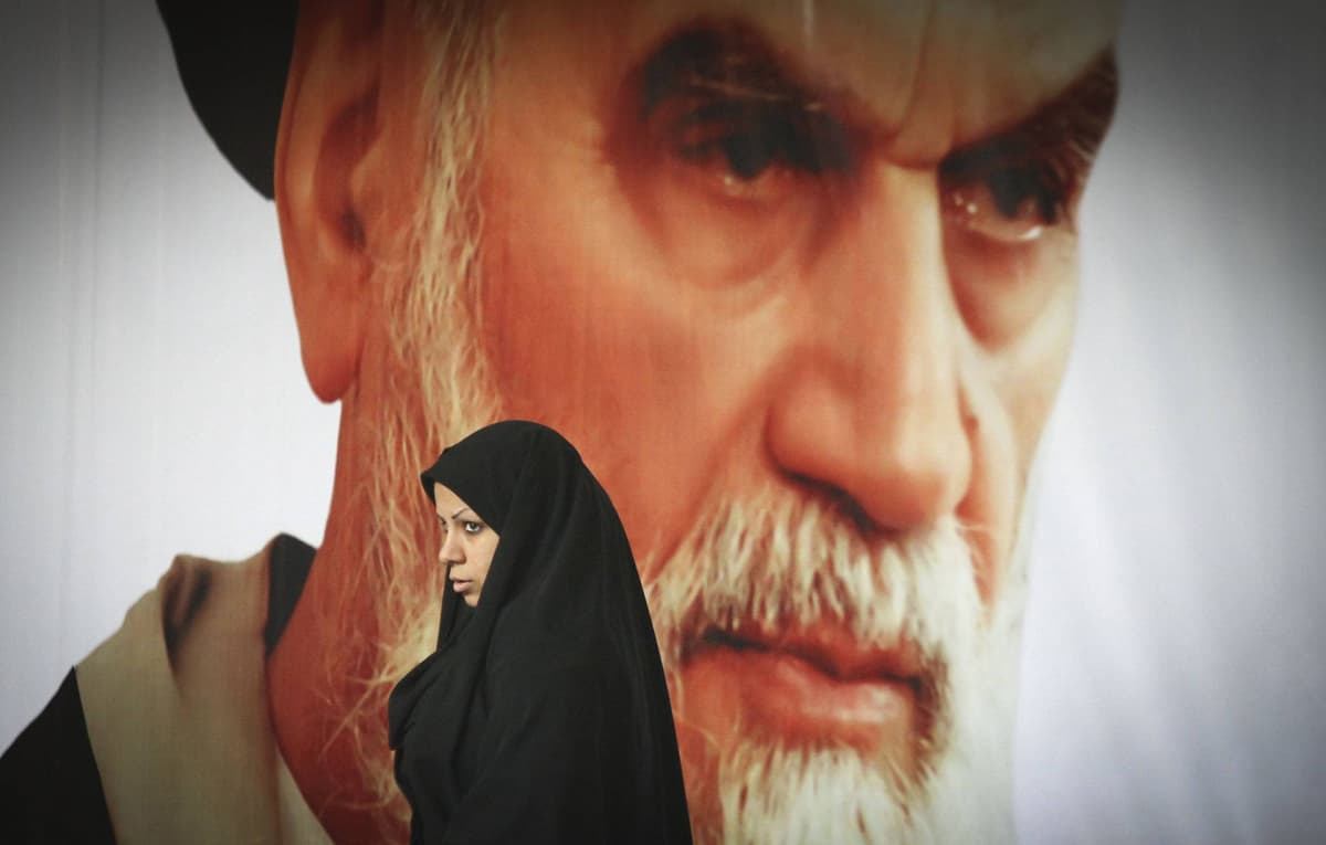 Nainen kävelee suuren Ayatollah Ruhollah Khomeini kuvan ohitse.