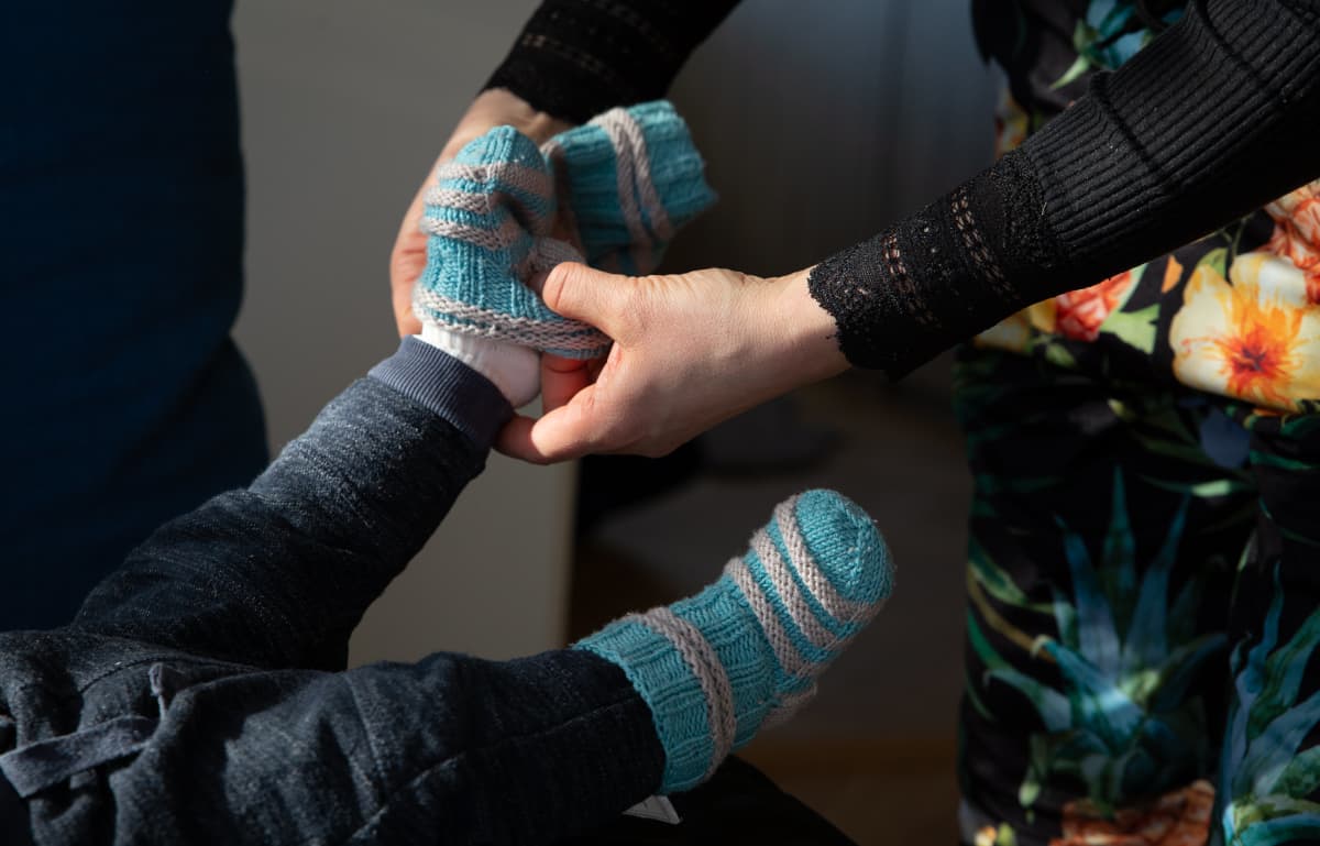 Eeva Kalmanlehto pukee vauvalleen villasukkia.