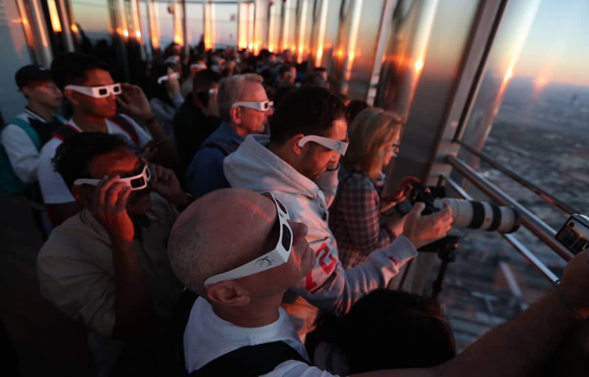 Ihmiset ihastelivat rengasmaista auringonpimennystä Burj Khalifa -pilvenpiirtäjän korkeuksissa Dubaissa.