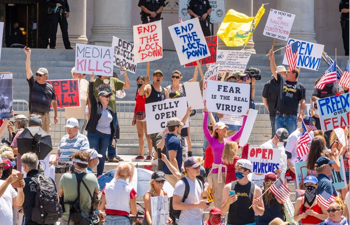 Noin 30 joukko kyltteineen ja Yhdysvaltain lippuineen kaupungintalon edessä.  