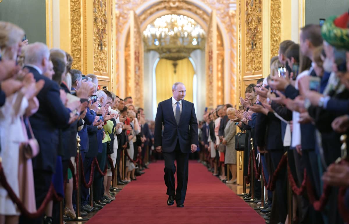 presidentti Vladimir Putin kävelee kultaisessaa salissa, ympärillä yleisöä.