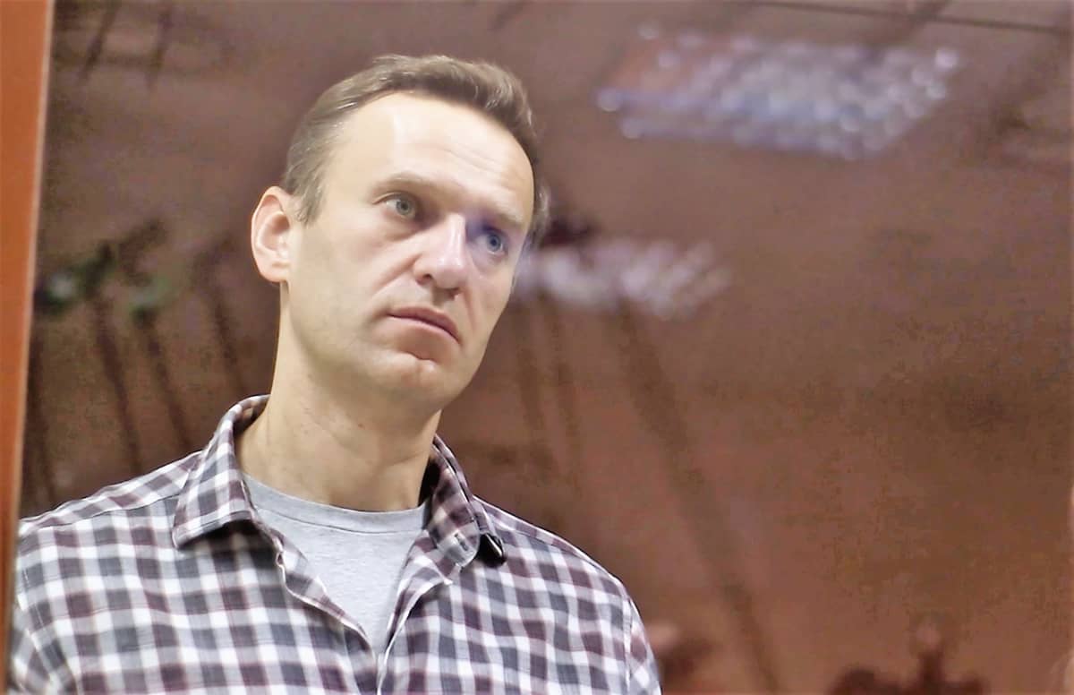 Aleksei Navalnyi seisoo ruutupaidassa lasikopissa oikeussalissa.