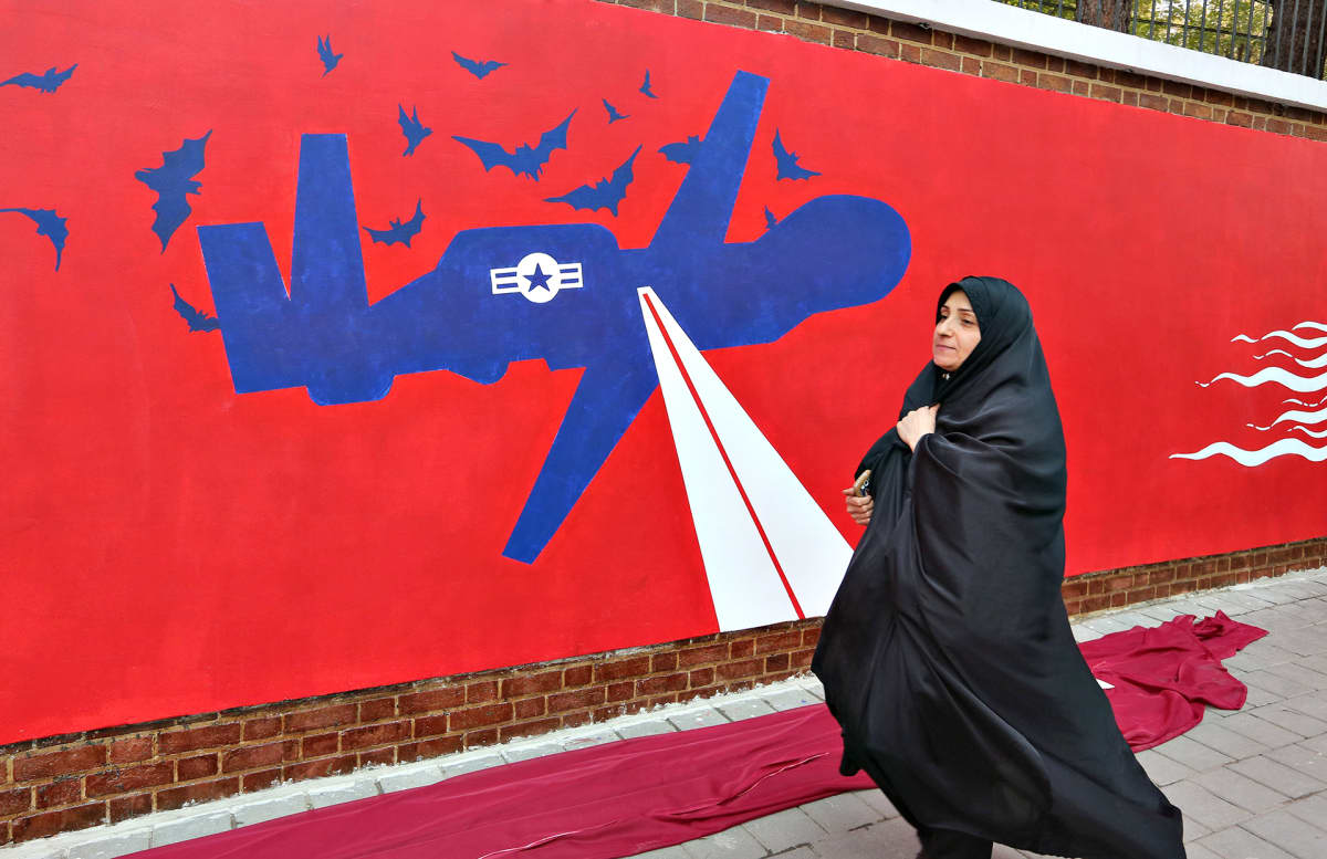 Iranilainen nainen kävelee entisen Yhdysvaltain lähetystörakennuksen ohi Teheranissa 2. marraskuuta. Tiiliseinään on maalattu kantaaottava muraali.