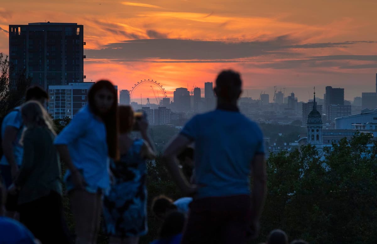 Ihmiset katsovat auringonlaskua Lontoossa.