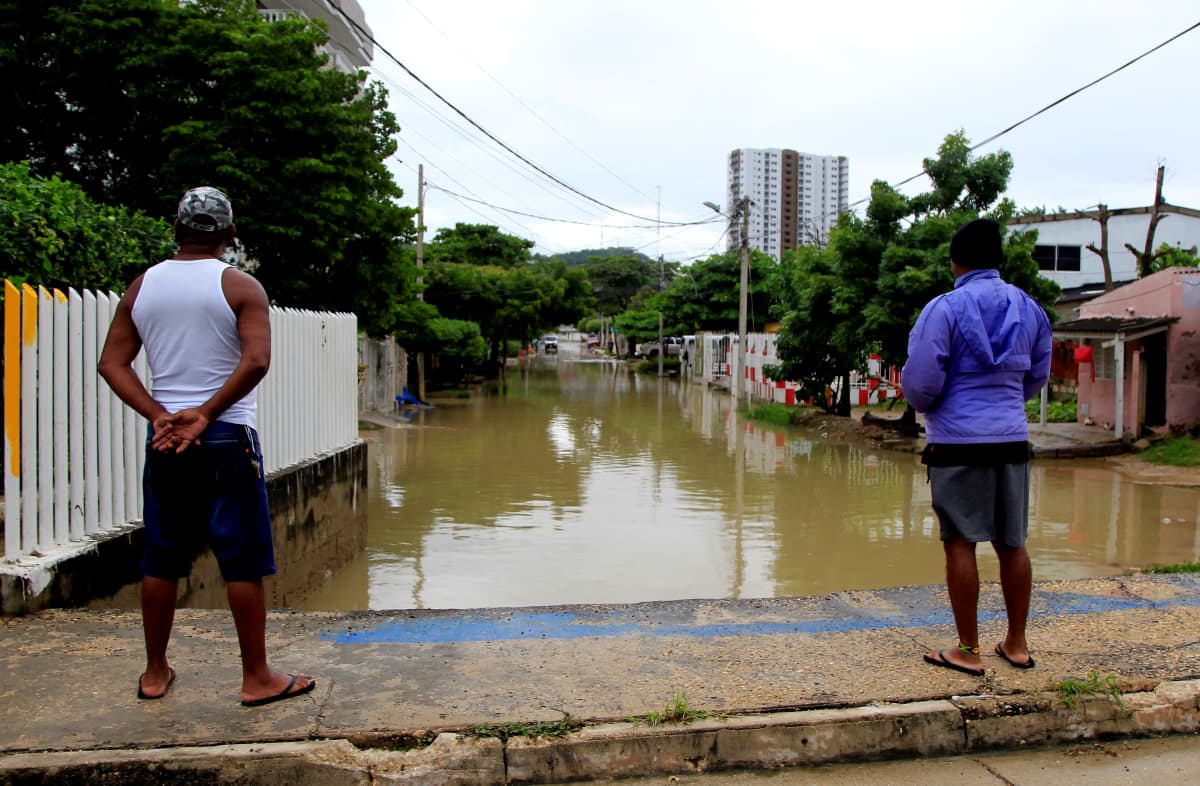 Kaksi kolumbialaista miestä katselee hirmumyrsky Iotan aiheuttamia tulvavahinkoja turistikaupunki Cartagenan lähiössä.