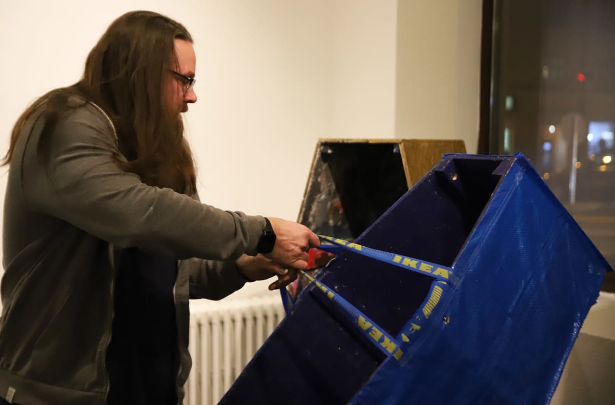 Taiteilija Ilmari Wärri kantaa Ikea-kasseilla päällystettyä arkkua.