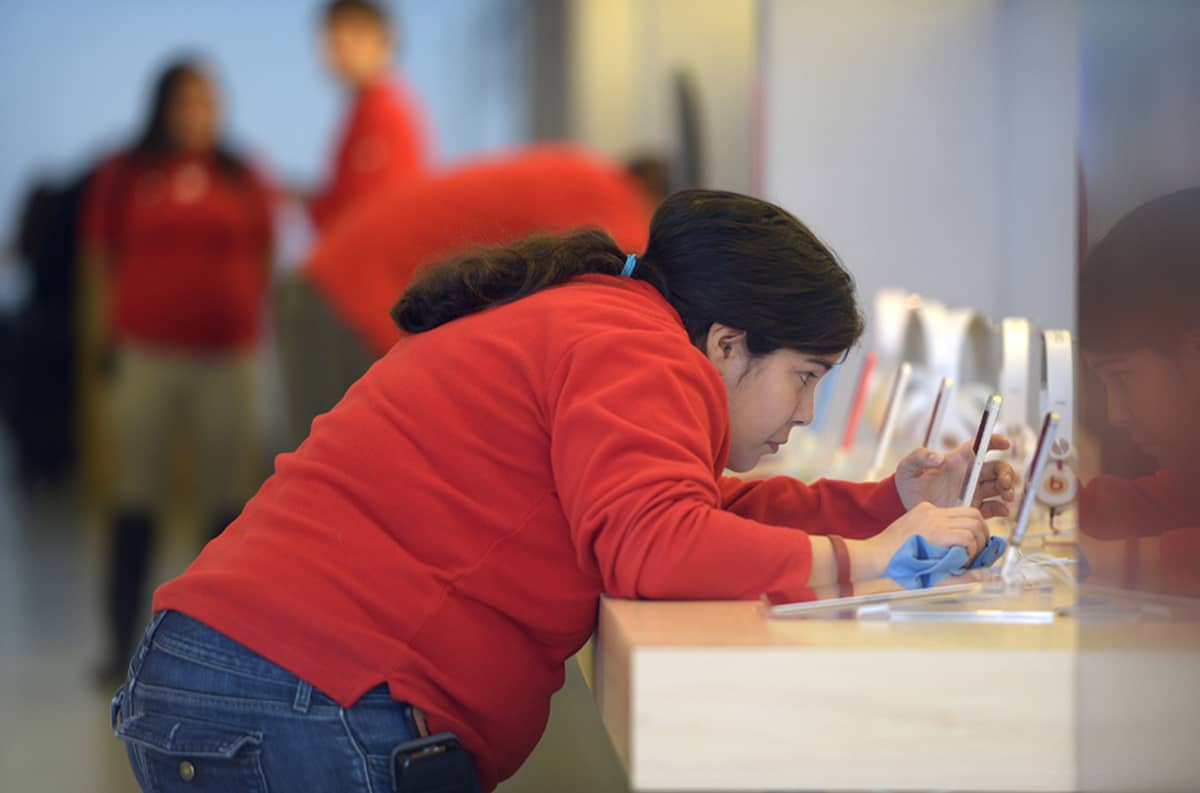 Myyjä puhdistaa älypuhelimia Applen myymälässä..