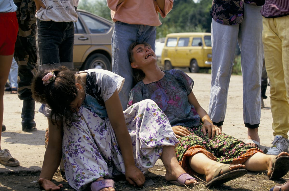 Bosnialaisnaiset itkevät kuultuaan läheistensä kuolleen Srebrenican joukkomurhassa heinäkuussa 1995. Naiset istuvat kuvan etualalla maassa, heidän takanaan on seisovia ihmisiä.