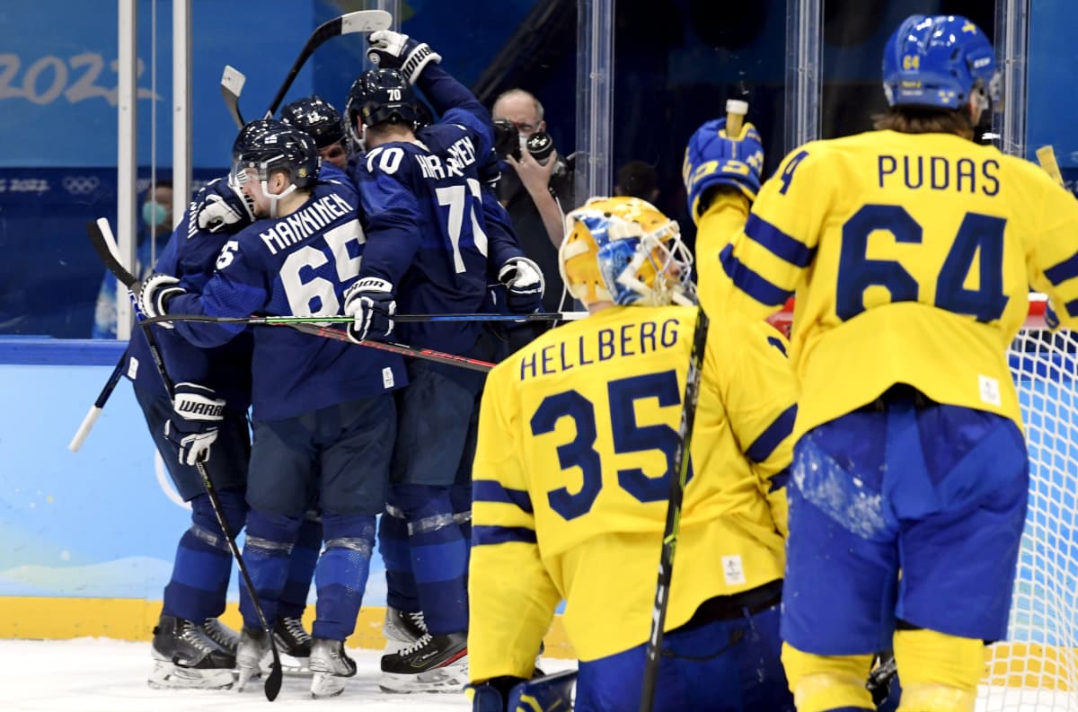 Ruotsin maalivahti Magnus Hellberg ja puolustaja Jonathan Pudas ihmettelevät maaliin mennyttä kiekkoa. Taustalla Suomen pelaajat juhlivat täysosumaa halaillen toisiaan.