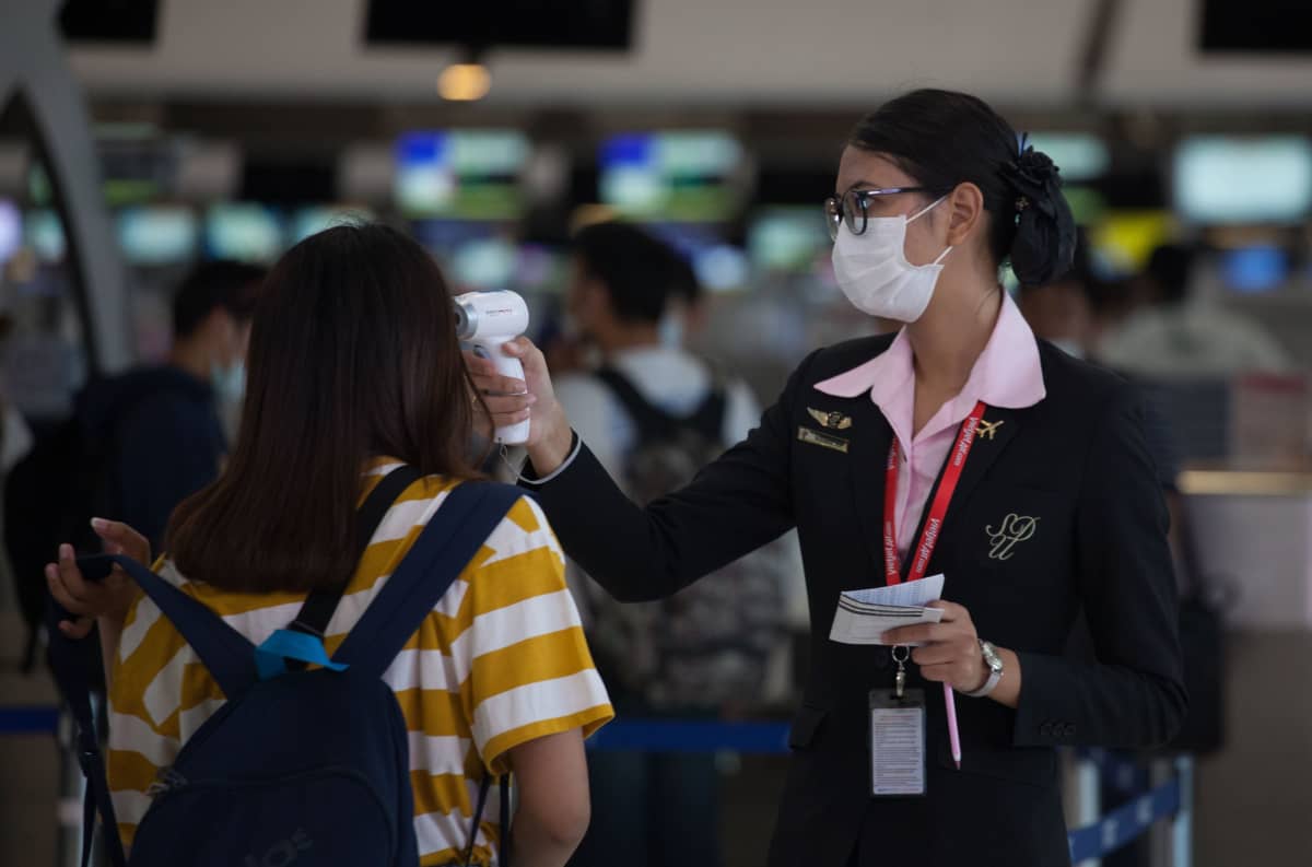 Lentokenttävirkailija mittasi matkustajalta kuumetta Suvarnabhumin lentokentällä Thaimaassa.