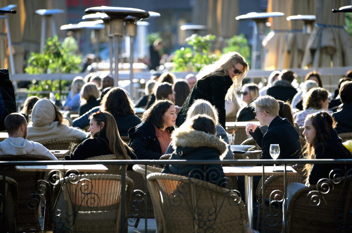 Ihmiset istuvat ulkona ravintolan terassilla Tukholmassa.