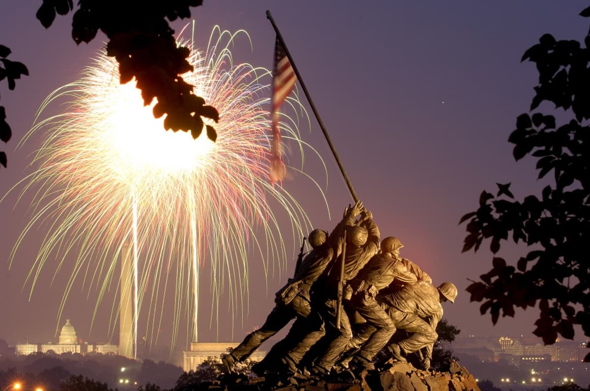 Muistomerkissä sotilaat työntävät maahan tankoa, jossa liehuu Yhdysvaltain lippu. Taustalla Washingtonin kaupunkia, taivaalla räiskähtää raketti. 