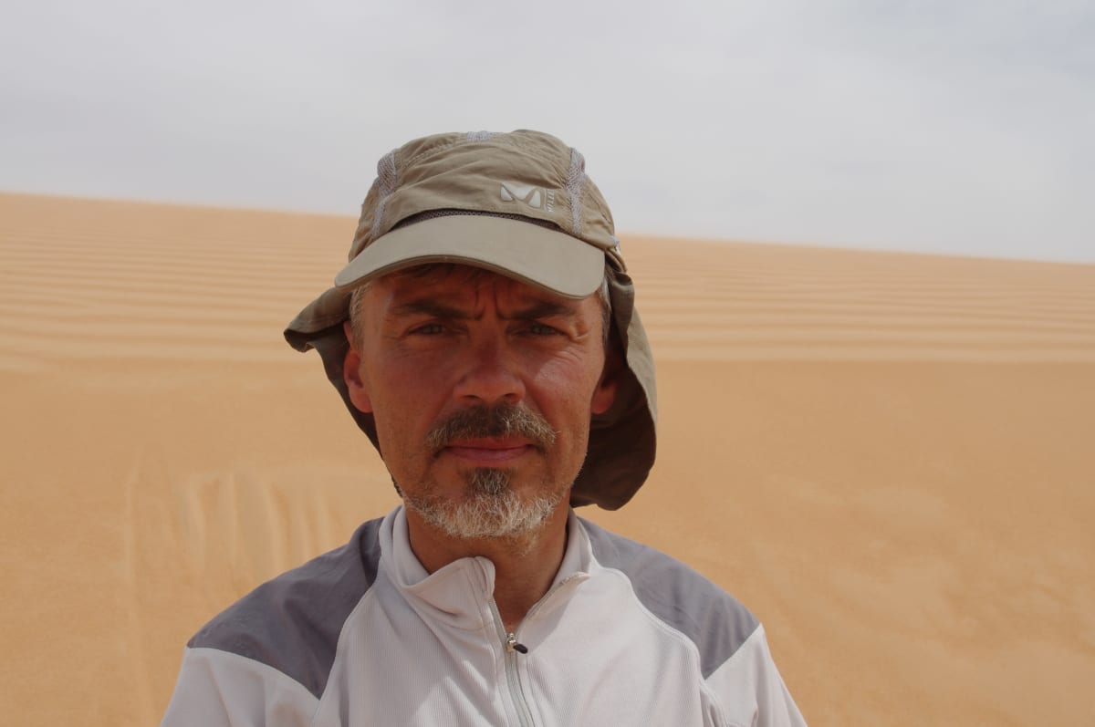Jukka Viljanen seisoo aavikolla ja katsoo kameraan.