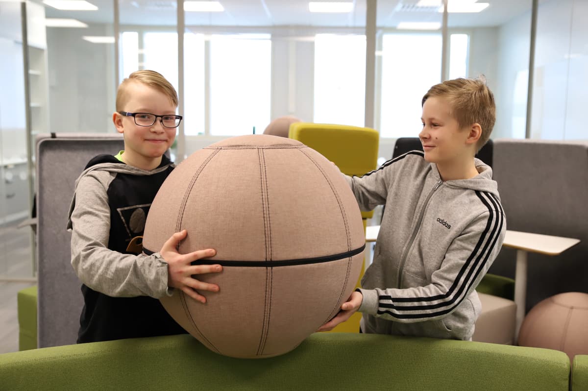 Nico Varis ja Eetu Kinnunen nostavat pallojakkaraa avoimessa opiskelutilassa.
