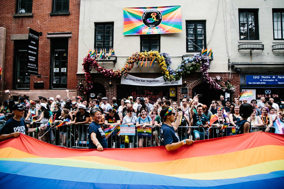 Sateenkaarilippu ja suuri ihmisjoukko Stonewall Innin edessä.