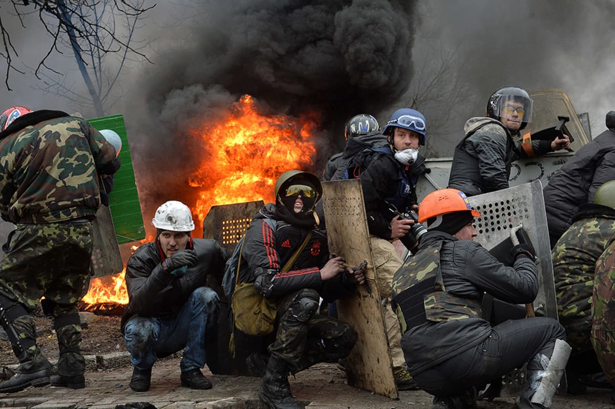 Mielenosoittajat suojautuvat barrikadin taakse Kiovan keskustassa.