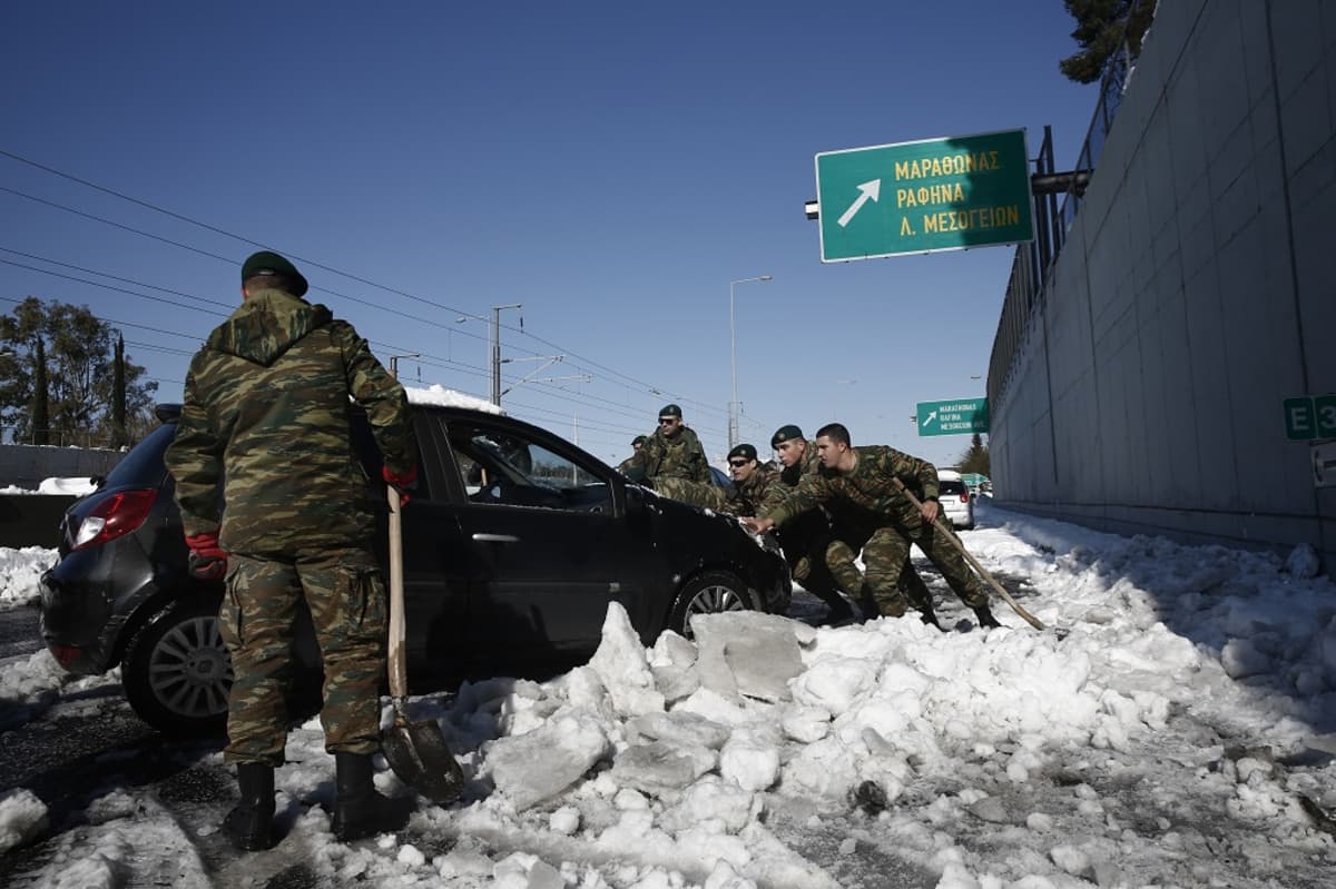 Kuvassa sotilaita työntämässä mustaa autoa. Etualalla seisoo sotilas lapio kädessään. 