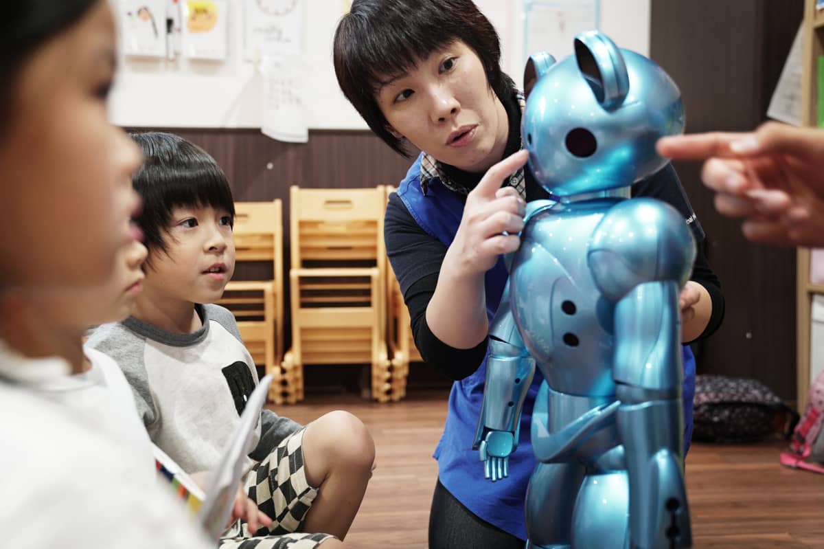Päiväkodin opettaja Hiromi Yamamoto näyttää, mihin robottia pitää koskettaa, kun se mittaa ruumiinlämmön.