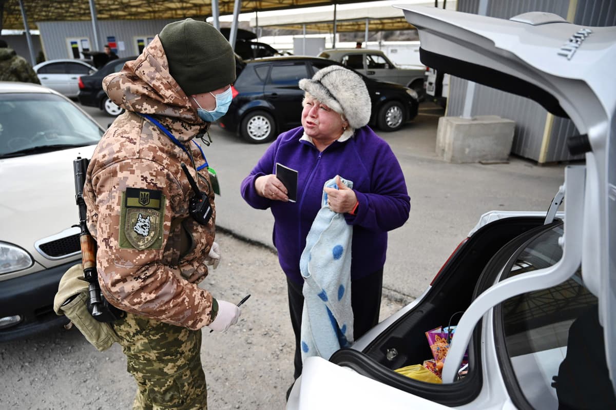 Ukrainalainen rajavartija tarkistaa rajalla naista.