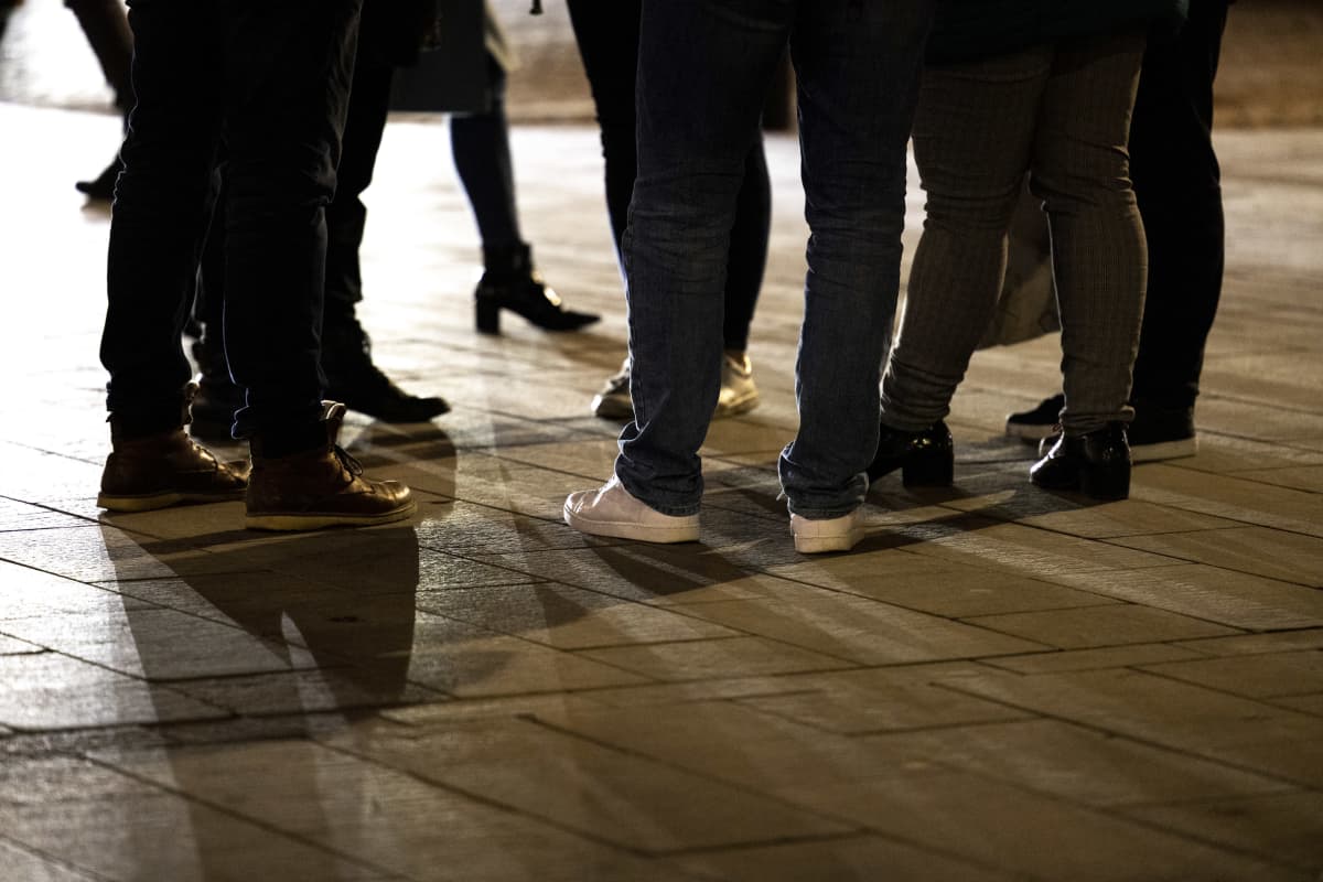 Ihmisryhmä seisoo kadulla, vain jalat näkyvät kuvassa.