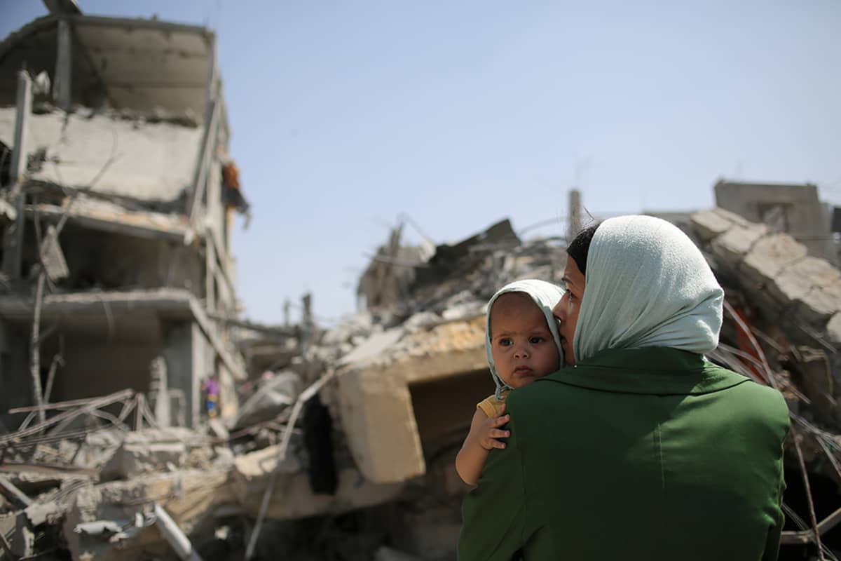Palestiinalaisäiti katseli Israelin iskujen tuhoamien talojen raunioita Beit Hanunin kaupungissa Gazan kaistalla perjantaina.