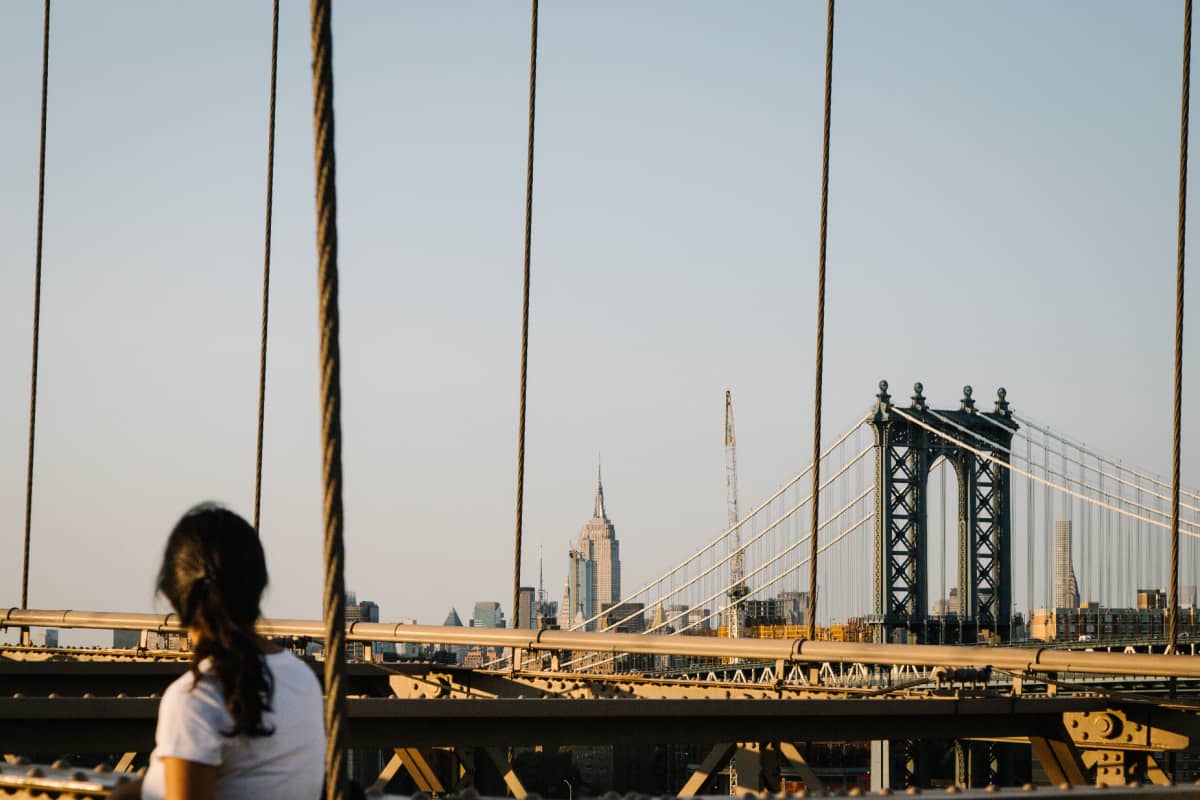 Nainen katsoo New Yorkin Brooklyn Bridgelle Brooklynissa. Takana siintää kaupungin pilvenpiirtäjä, joukossaan Empire State Building.