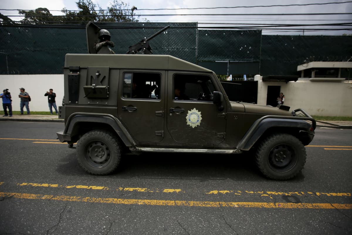 Kuvassa armeijan jeeppi, jonka kattoluukusta kurkistaa kypäräpäinen sotilas ase tanassa.