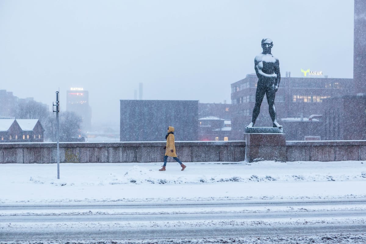 Henkilö kävelee Hämeensillalla lumisateessa keskustassa Tampereella 20.1.2022. 