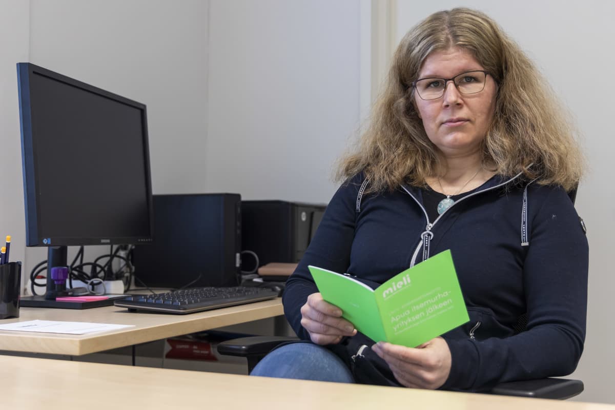Länsi-Pohjan sairaanhoitopiirin psykologi Elina Valkonen lukee Mieli ry:n esitettä työhuoneessaan.