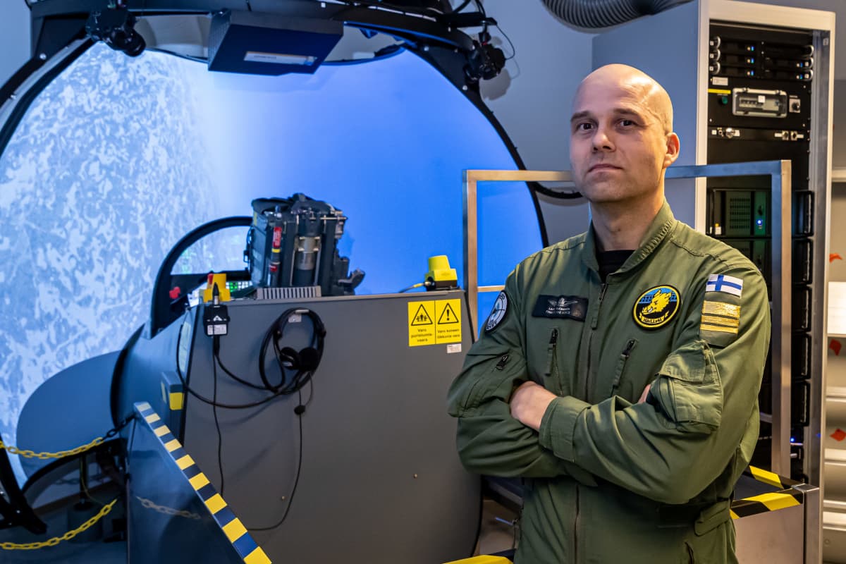 Ilmasotakoulun Hävittäjälentolaivue 41:n komentaja everstiluutnantti Lauri Suominen seisoo Hawn -lentosimulaattorin edustalla. Taustalla oppilas lentoharjoituksessa.