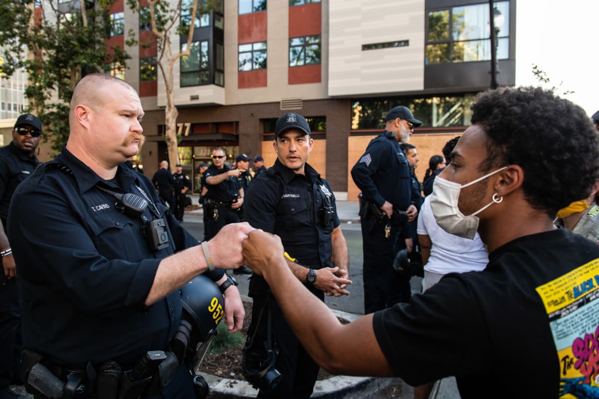 Valkoinen poliisi tekee mustan mielenosoittajan kanssa nyrkkitervehdyksen Oaklandissa, Kaliforniassa, 2. kesäkuuta 2020