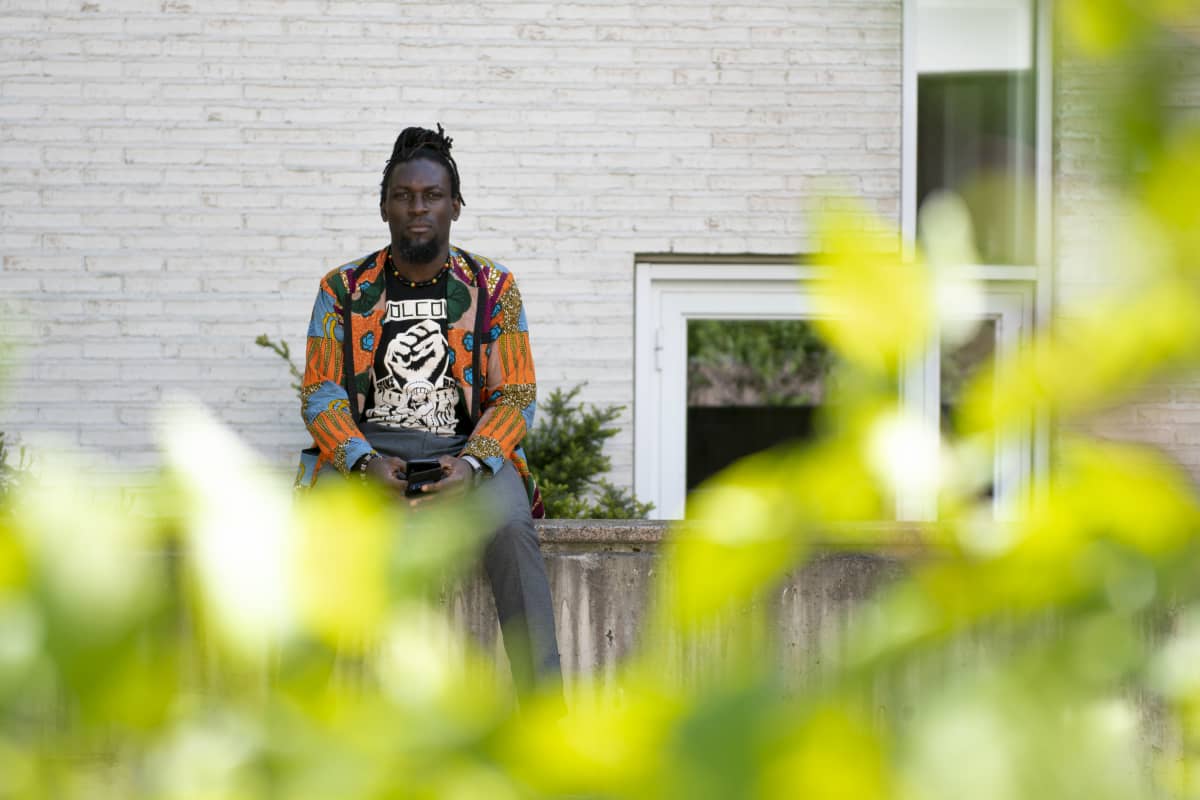 Kuvassa on tutkija Aminkeng Atabong Alemanji istuu betoniaidalla, etualalla lehtiä.