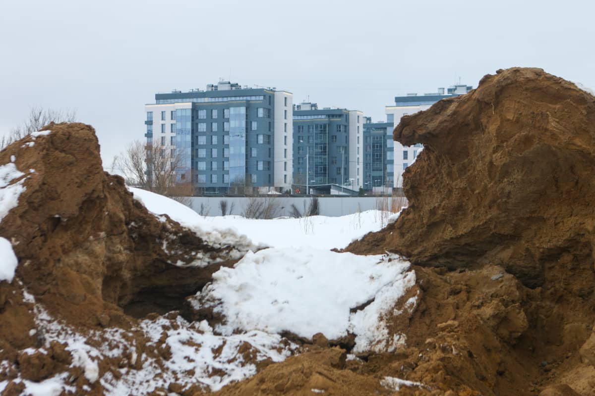 Hiekkakasan takana näkyy uusia kerrostaloja Pietarissa osoitteessa Primorskij Prospekt 78. 