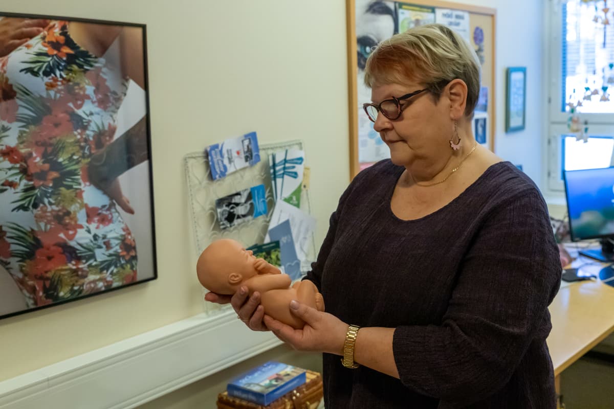 Sovatek-säätiön Äitinä yhdessä -hankkeen sosiaalityöntekijä Anne Pitkänen pitelee käsissään pientä nukkea, joka kuvastaa millainen on raskausviikon 28 ikäinen sikiö.