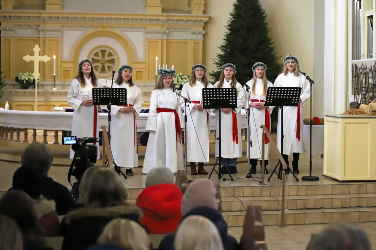 Mikkelin lukion Lucia-juhla Mikkelin tuomiokirkossa joulukuussa 2021, Lucia-kuoro laulaa yleisön edessä.