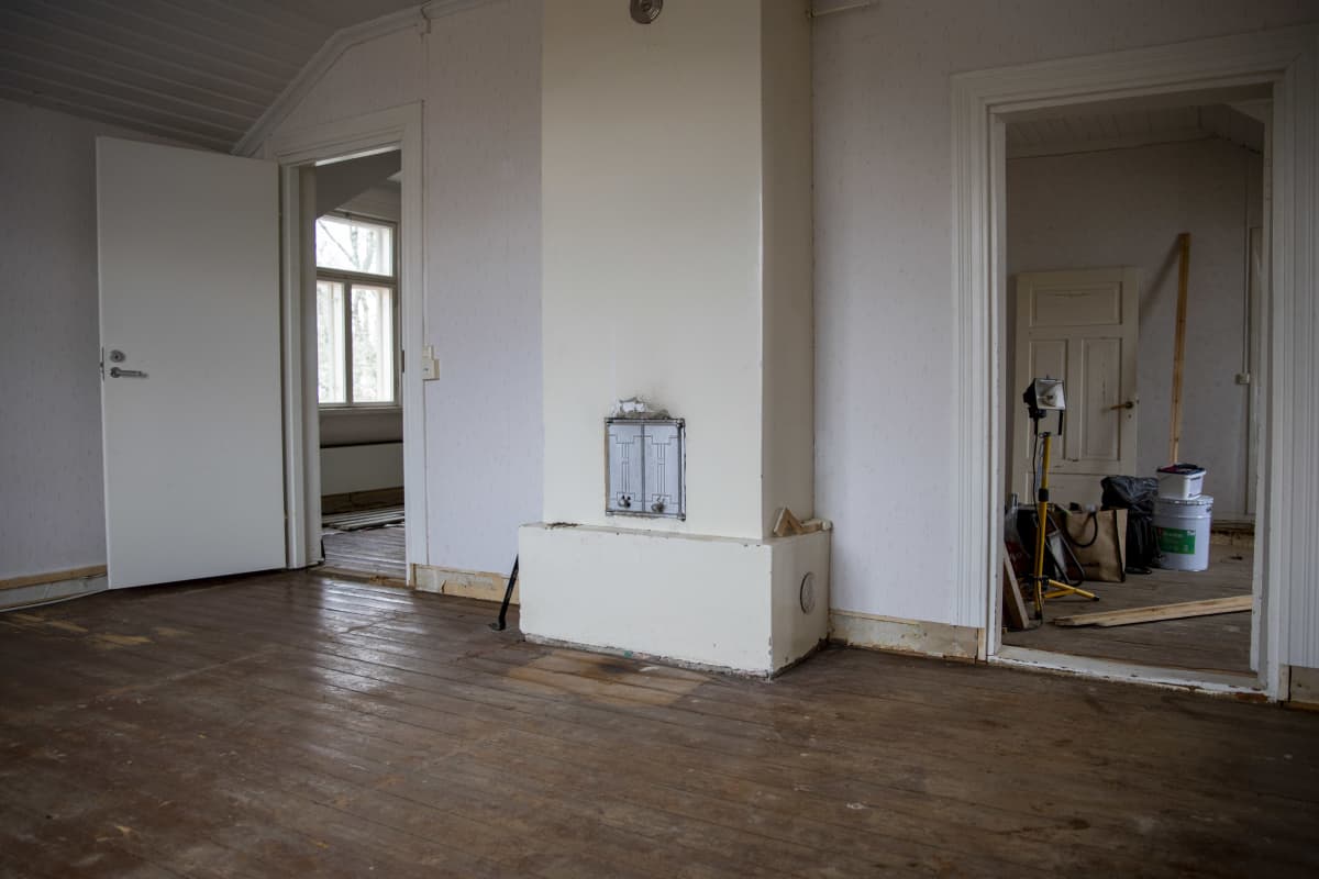 vanhan talon yläkerran tyhjässä huoneessa on kulunut puulattia. Keskellä huonetta on takka, jonka molemmin puolin on ovet huoneisiin