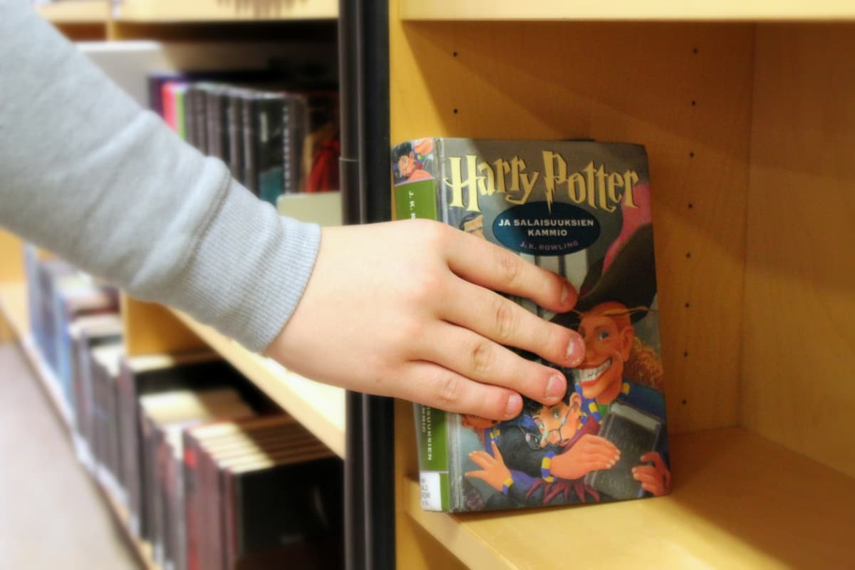 Käsi nostaa kirjaston hyllystä Harry Potter -kirjan.