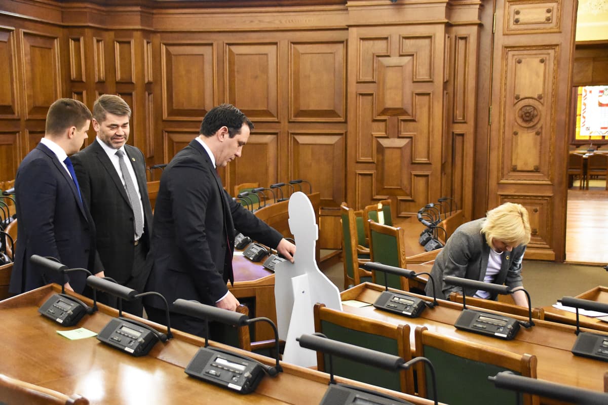 Uuden konservatiivisen puolueen kansanedustaja Sandis Riekstinš asettaa pahviukon Juris Jurašsin istumapaikalle ennen parlamentin istunnon alkamista.