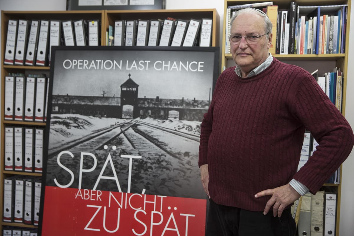 Efraim Zuroff seisoo  Operaatio viimeinen mahdollisuus -kampanjan julisteen edessä.
