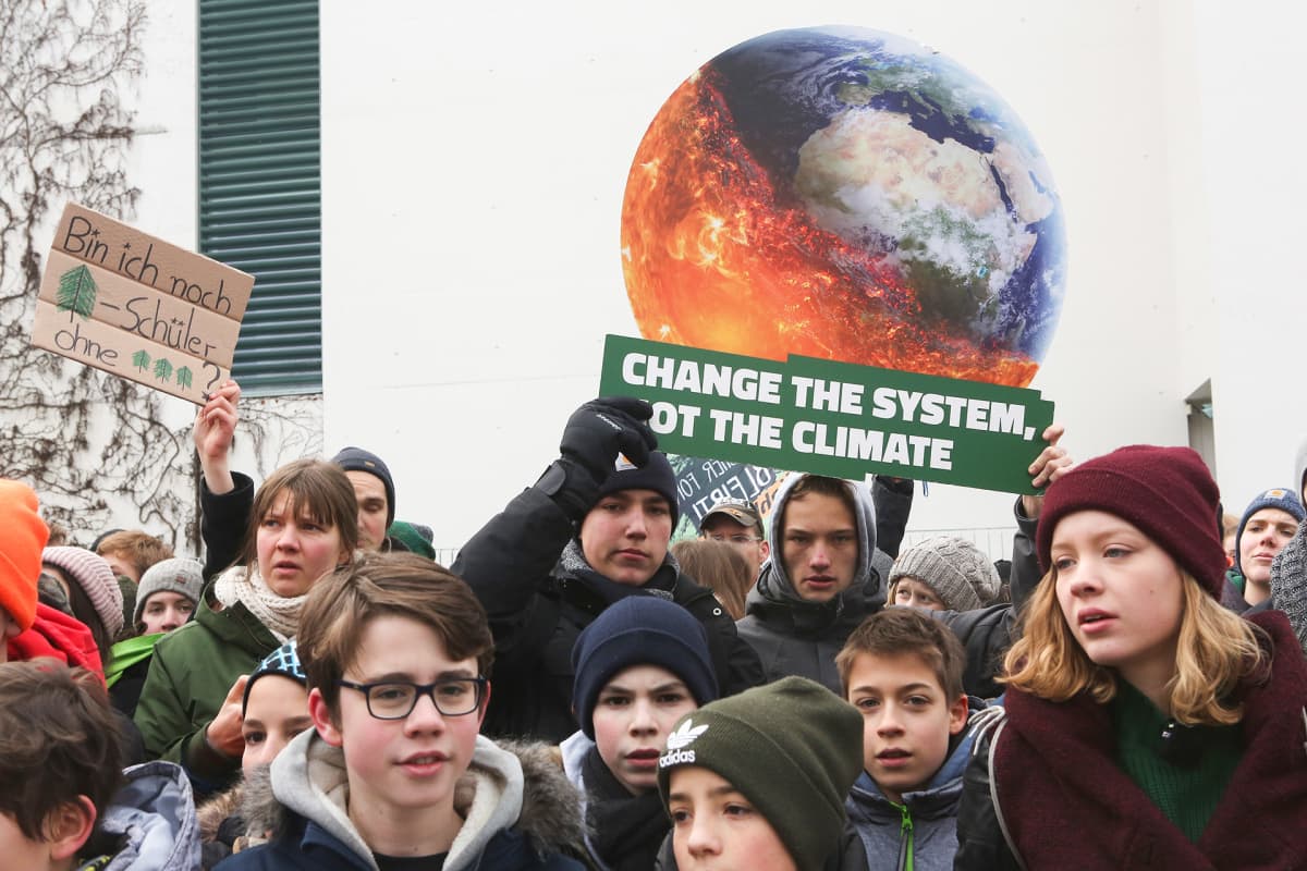 Nuoria ja lapsia mielenosoituksessa, taustalla kyltti, jossa palava maapallo.