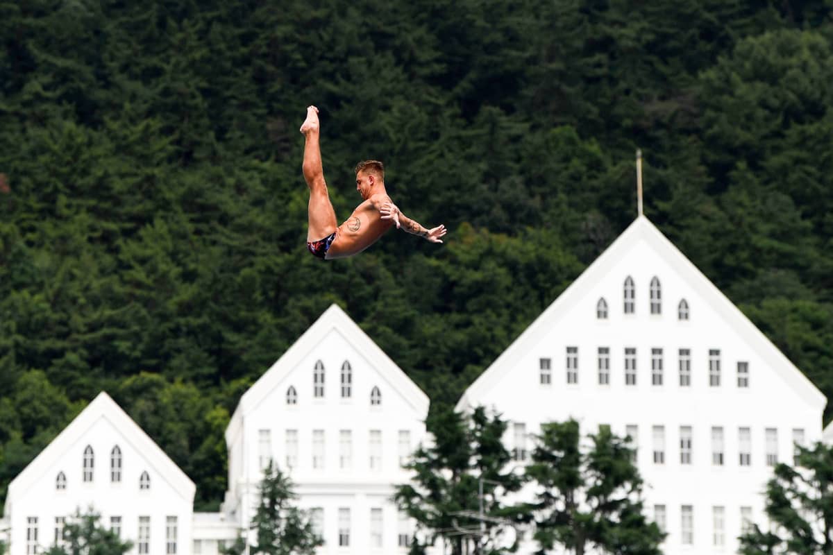 Venäläinen Nikita Fedotov ilmassa talojen kattojen yllä uimahyppyä suorittaen.