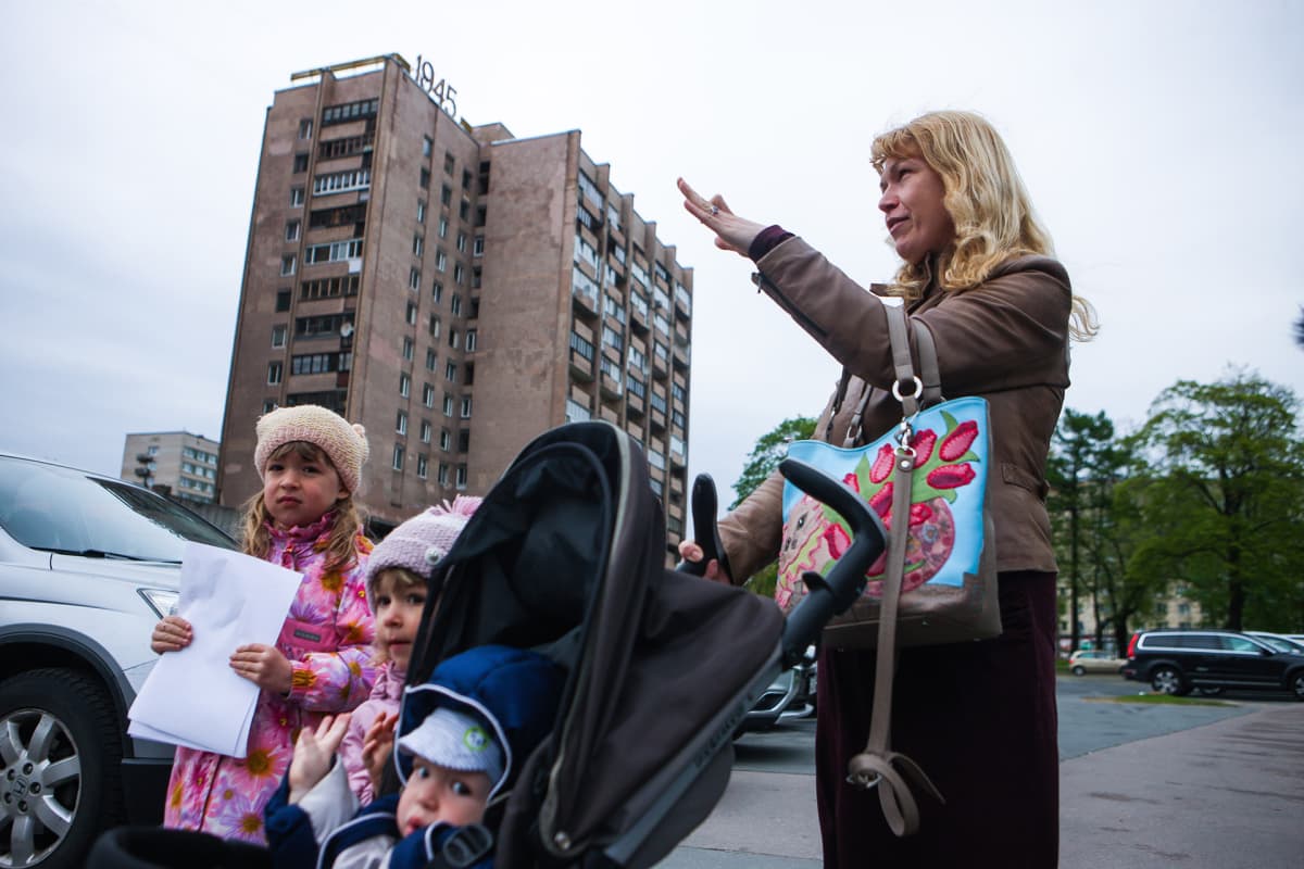 Antonina Jelisejeva ja hänen lapsensa etualalla, taka-alalla neuvostoaikainen rakennus.