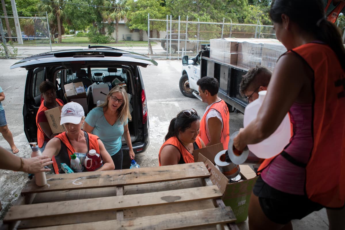 Rachel Costigan ja avustustyöntekijät kantavat autosta tarvikkeita.