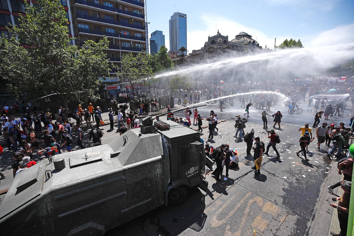 Poliisi hajottaa mielenosoitusta vesitykein Santiagossa.