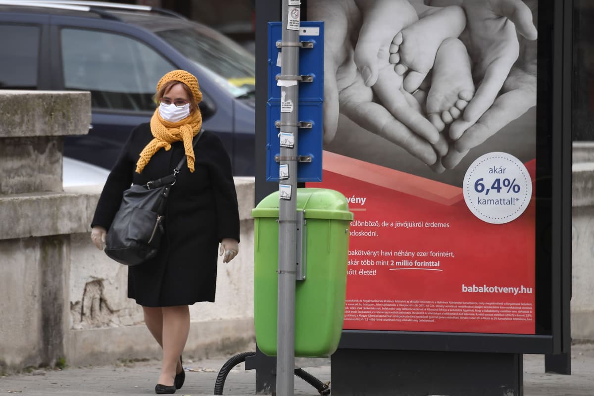 Kasvonsa suojannut nainen kävelee bussiasemalla 26. maaliskuuta Budapestissä Unkarissa.