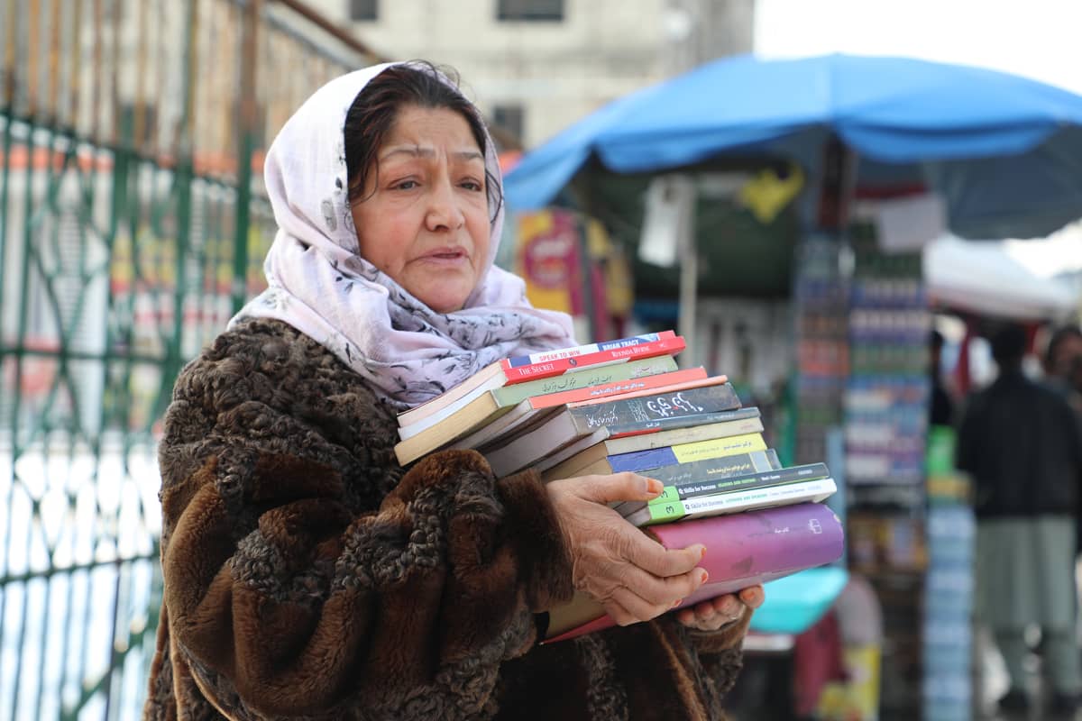Kirjoja myyvä Fereshta Sadeqi seisoo Kabulin keskustassa. Maan taloudellinen ahdinko tarkoittaa, että asiakkaita ei enää löydy.