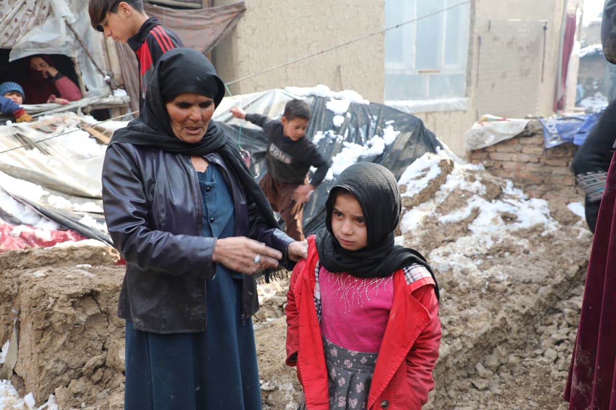 Leski Mehr Gul näyttää lumisateessa tuhoutuneen talonsa raunioita tyttärensä kanssa Kabulin laidalla.