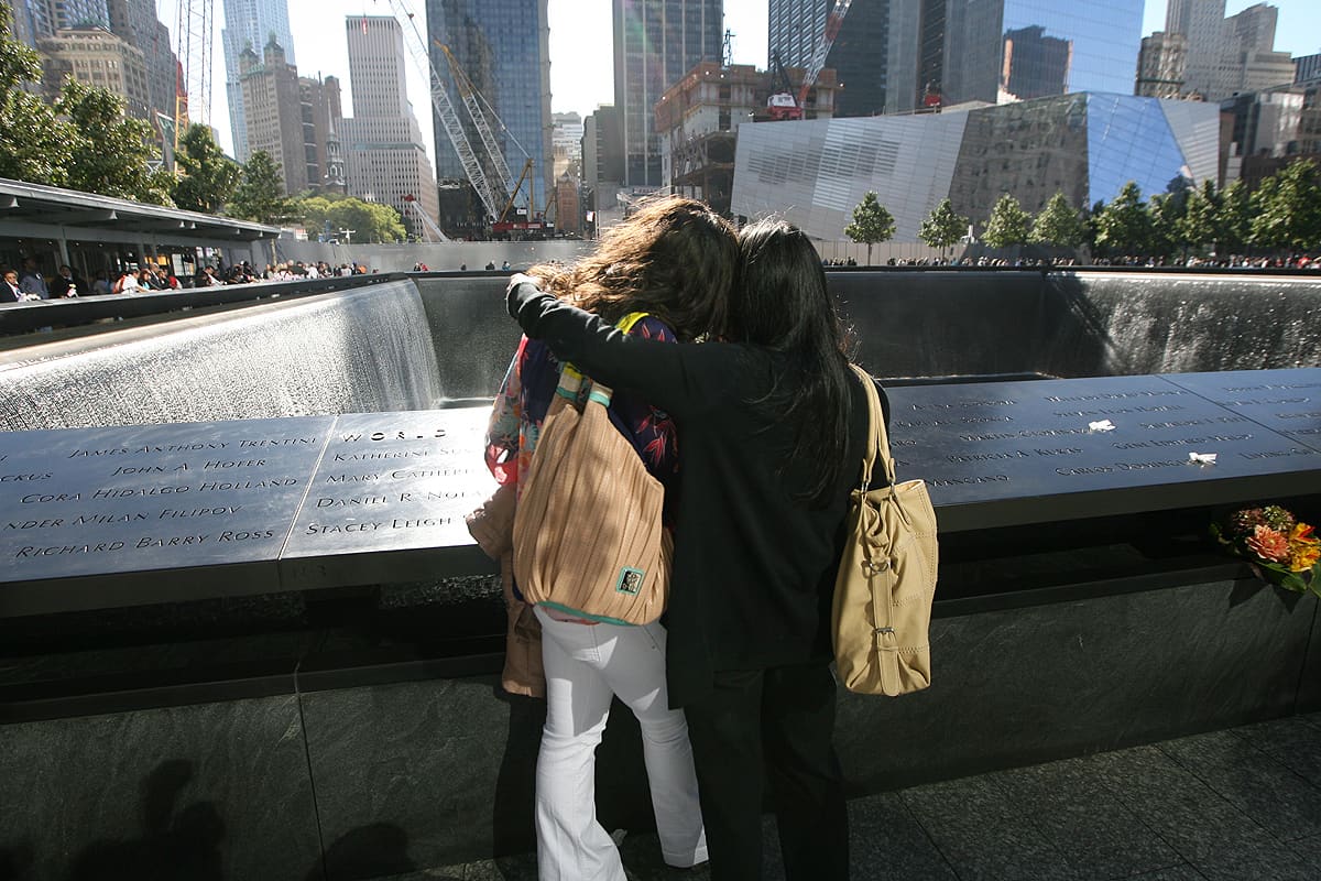 Kaksi naista lohduttaa toisiaan World Trade Centerin iskujen muistopaikalla.