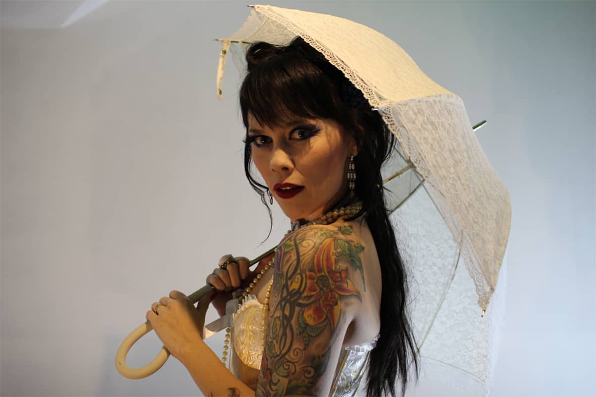 Burleskiesiintyjä Tanja Karppi poseeraa esiintymisasussaan päivänvarjon kanssa. 