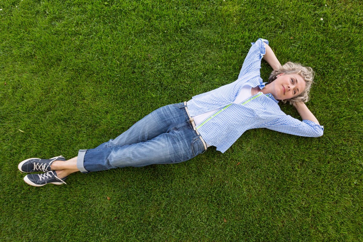 Nainen makaa nurmikolla